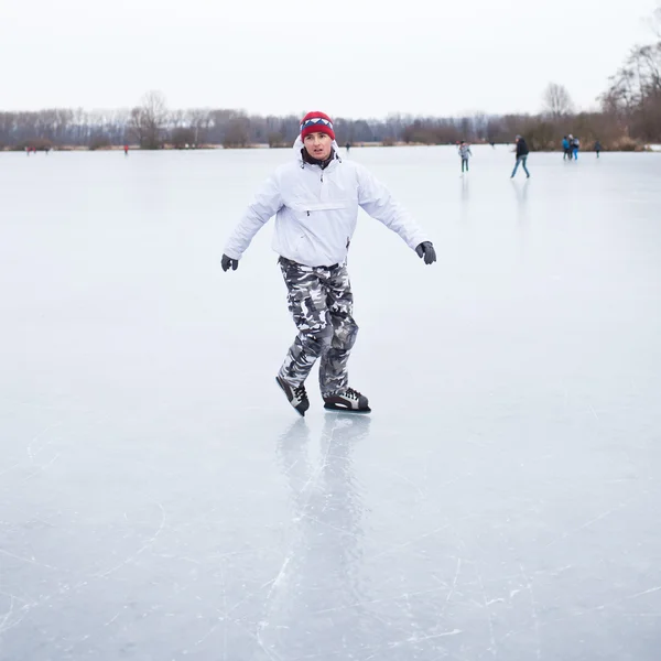 Guapo joven patinaje sobre hielo al aire libre en un estanque en un wi nublado —  Fotos de Stock