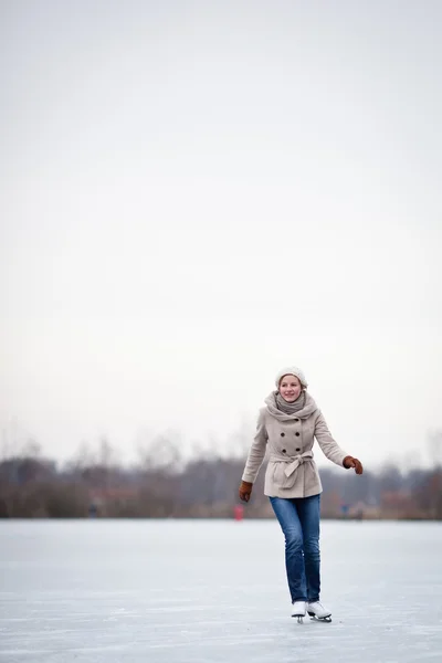 Jovem mulher patinação no gelo ao ar livre em uma lagoa — Fotografia de Stock