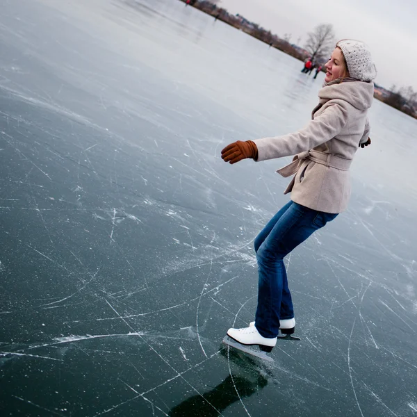 Mujer joven patinaje sobre hielo al aire libre en un estanque — Foto de Stock