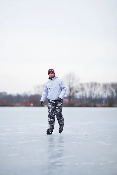 Przystojny, młody człowiek lodu łyżwiarskie na zewnątrz na stawie na słabe wi — Zdjęcie stockowe