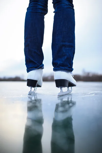 Jovem mulher patinação no gelo ao ar livre em uma lagoa em um inverno gelado — Fotografia de Stock