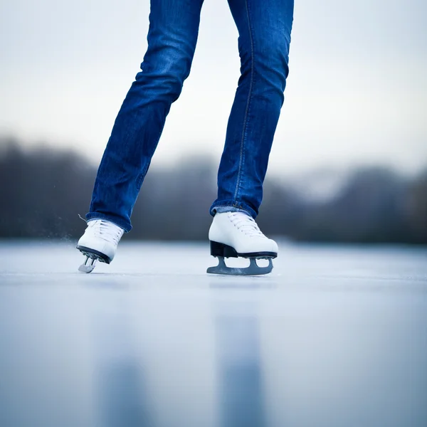 Mujer joven patinaje sobre hielo al aire libre en un estanque en un invierno helado —  Fotos de Stock