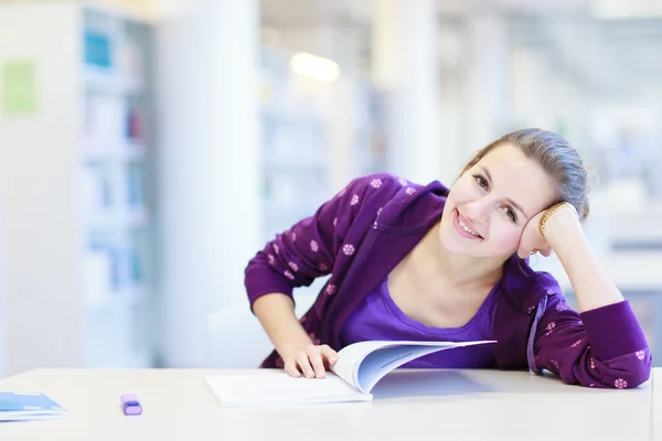 Kvinnliga collegestudent i ett bibliotek — Stockfoto