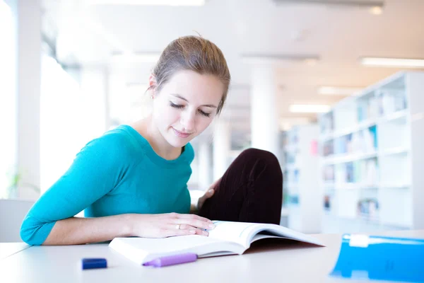 Kvinnliga collegestudent i ett bibliotek — Stockfoto