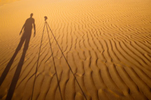 Shadow of a photographer standing next to his tripod cast — Stock Photo, Image
