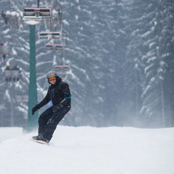 Jonge man snowboarden skiën op een besneeuwde winterdag — Stockfoto