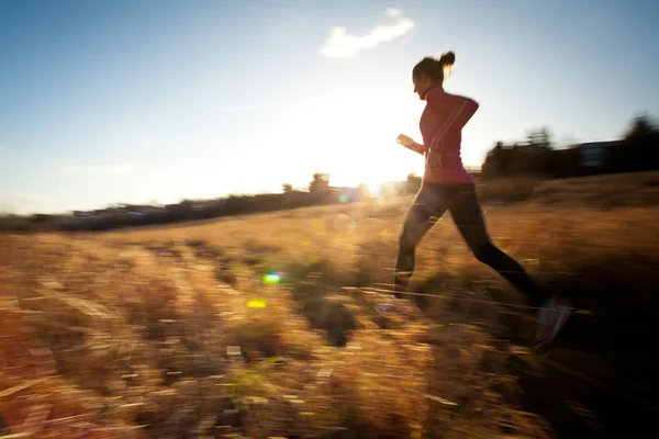 Junge Frau läuft an einem schönen, sonnigen Winter- / Herbsttag im Freien — Stockfoto