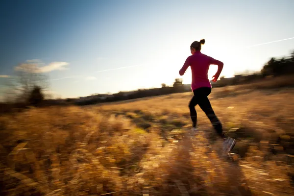 Молодая женщина бежит на открытом воздухе в прекрасный солнечный день зимы / осени — стоковое фото