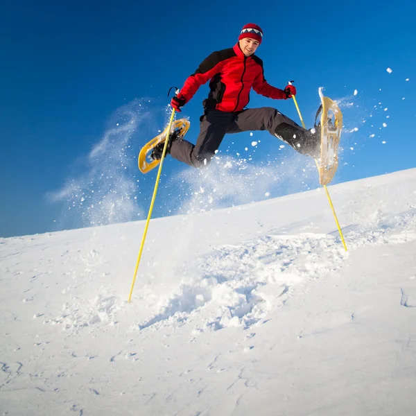 Молодой человек развлекается, катаясь на снегоступах — стоковое фото