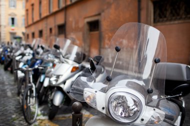 Row of motorbikes and scooters parked clipart