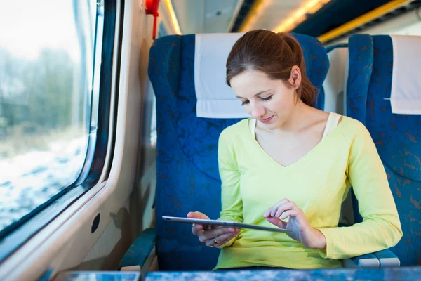 Ung kvinna med sin tablet PC när du reser med tåg — Stockfoto