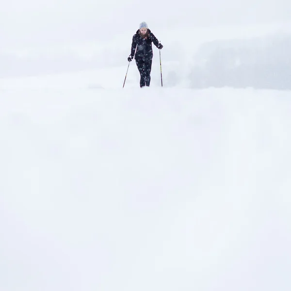 Jonge vrouw cross-country skiën op een besneeuwde winterdag — Stockfoto