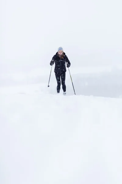 Молодая женщина катается на лыжах в снежный зимний день — стоковое фото