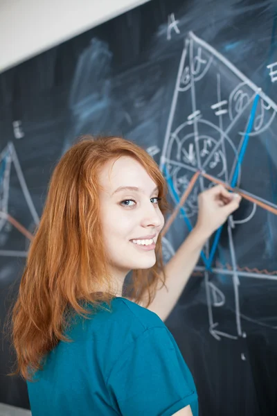 Csinos, fiatal főiskolai hallgató írásban a táblára — Stock Fotó