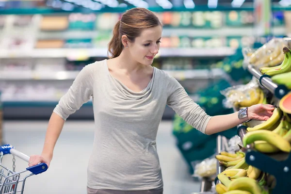 Pretty, young woman shopping for fruits and vegetables Royalty Free Stock Photos