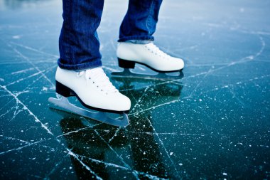 Young woman ice skating outdoors on a pond clipart