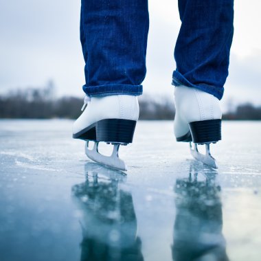 Young woman ice skating outdoors on a pond clipart