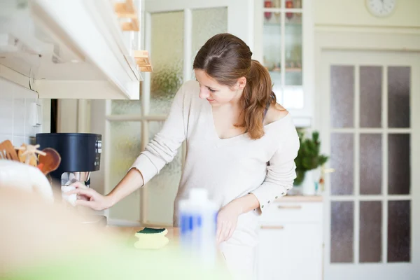 Mladá žena dělá domácí práce, uklízí kuchyň — Stock fotografie