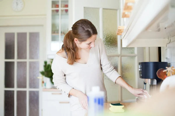 Молода жінка робить домашнє завдання, прибирає кухню — стокове фото