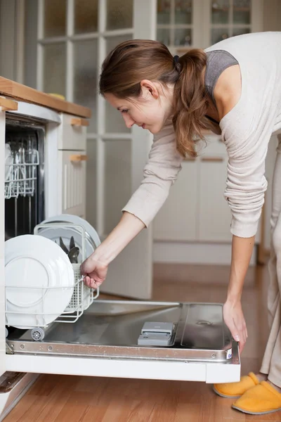 Молода жінка використовує посудомийну машину — стокове фото