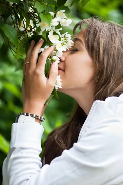 Schöne junge Frau, die weiße Jasminblüten riecht — Stockfoto