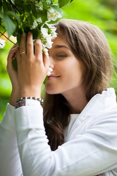 Belle jeune femme sentant les fleurs de jasmin blanc — Photo