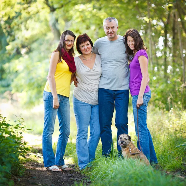 Familienporträt - vierköpfige Familie mit niedlichem Hund im Freien — Stockfoto