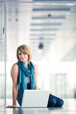 Pretty young female student with a laptop computer clipart