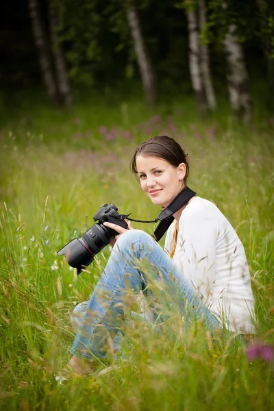 Mujer bastante joven con una cámara réflex digital al aire libre, tomando fotos — Foto de Stock