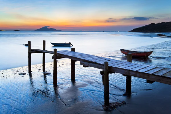 Západ slunce na dřevěném molu podél pobřeží — Stock fotografie