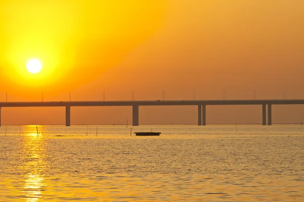 Pôr do sol sobre uma ponte com barcos em movimento — Fotografia de Stock
