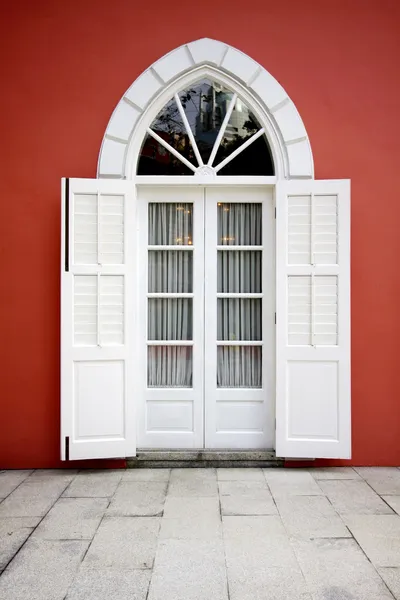 White door on red wall background — Stock Photo, Image