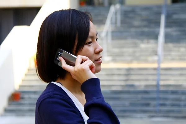 Asiatisk kvinna med mobiltelefon och talar — Stockfoto