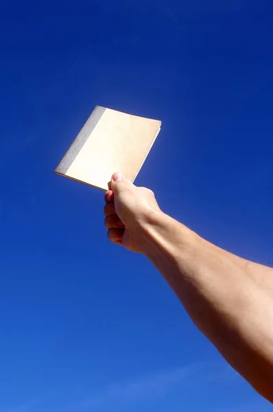 Sostiene un cuaderno bajo el cielo azul —  Fotos de Stock