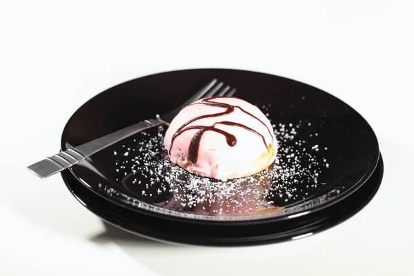 Розовый крем-кекс на черной тарелке — стоковое фото