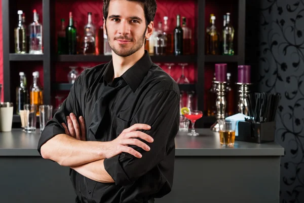 Barman in black standing at cocktail bar — Stock Photo, Image