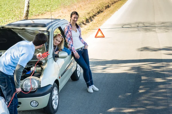 Auto vada muž pomáhá dvě kamarádky — Stock fotografie