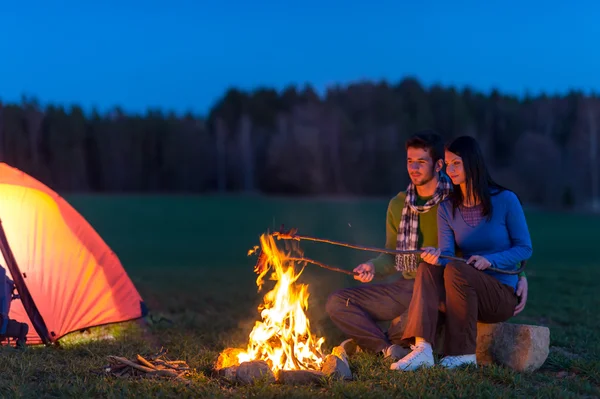 キャンプの夜のカップルをロマンチックなキャンプファイヤーで調理します。 — ストック写真