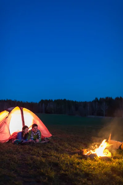 Camping noite casal deitado frente barraca fogueira — Fotografia de Stock
