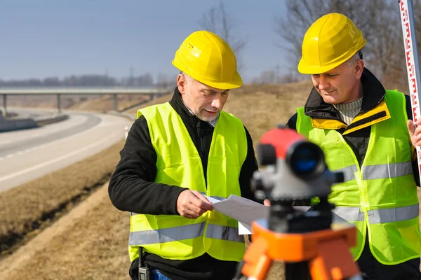 Geodesist two man theodolite stand highway — Stock Photo, Image