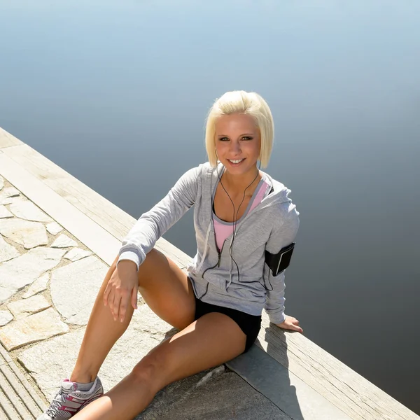 Sportlerin entspannt auf Steg sitzendes Wasser — Stockfoto