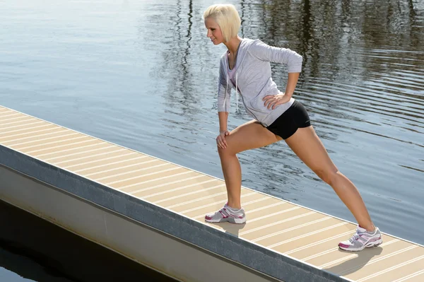 Sportlerin streckt Körper auf Seebrücke — Stockfoto