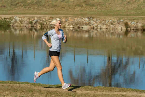 Running woman outdoor sport by river bank — Stock Photo, Image