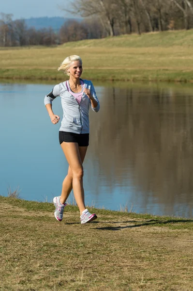 Running woman outdoor sport by river bank — Stock Photo, Image