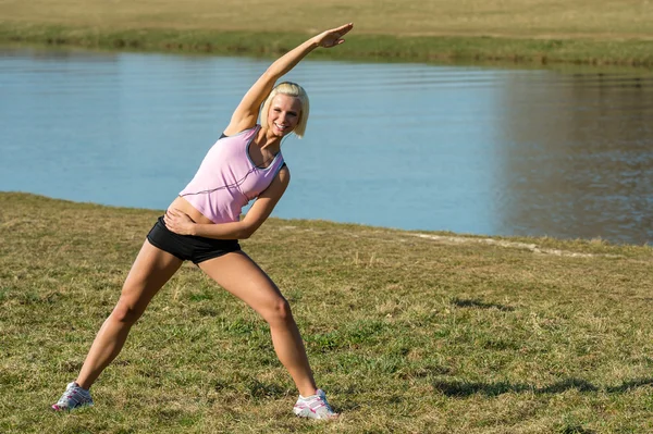 Junge Frau dehnt sich vor dem Joggen im Freien — Stockfoto