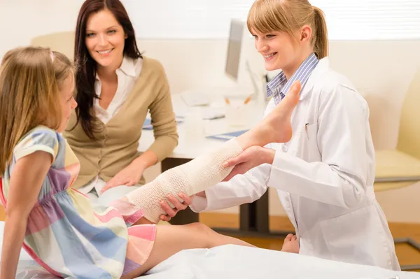 Pediatra sprawdzanie zepsuty bandaż dziewczyna noga — Zdjęcie stockowe