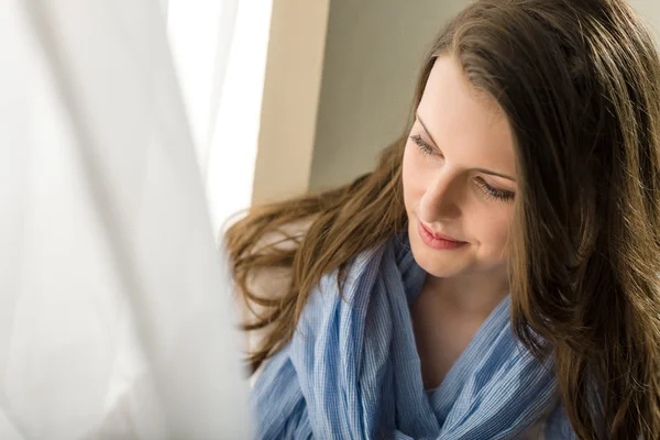 Брюнетка молодая женщина смотрит в окно — стоковое фото