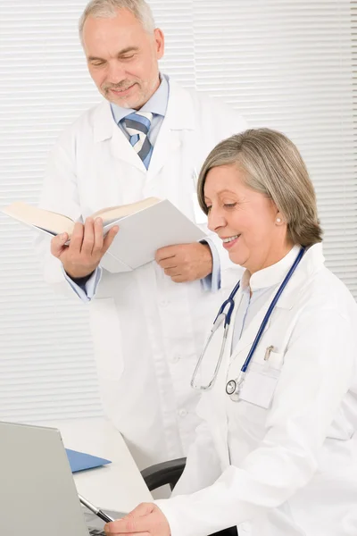 Médicos da equipe médica ler livro olhar computador — Fotografia de Stock