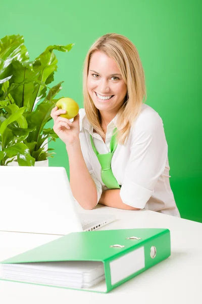 Kadın gülümsüyor tutun elma bitki yeşil ofis — Stok fotoğraf