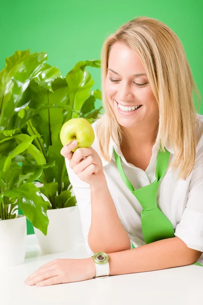 Πράσινο γραφείο γυναίκα χαμογελώντας λαβή apple φυτών — Φωτογραφία Αρχείου